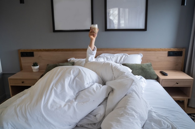 Hand holding a cup of coffee at home in bed