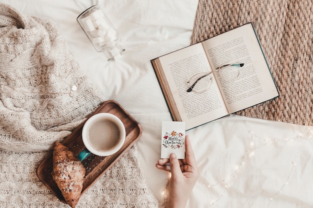 Hand holding cutaway near book, eyeglasses, food and plaid