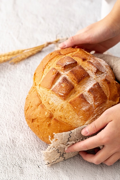 Hand holding delicious baked bread and hessian cloth