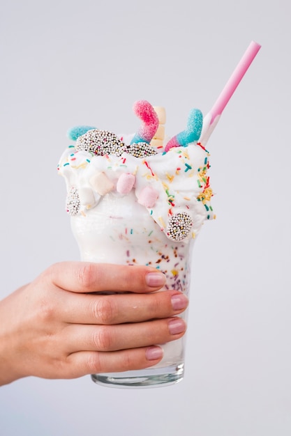 Free photo hand holding a delicious milkshake with plain background