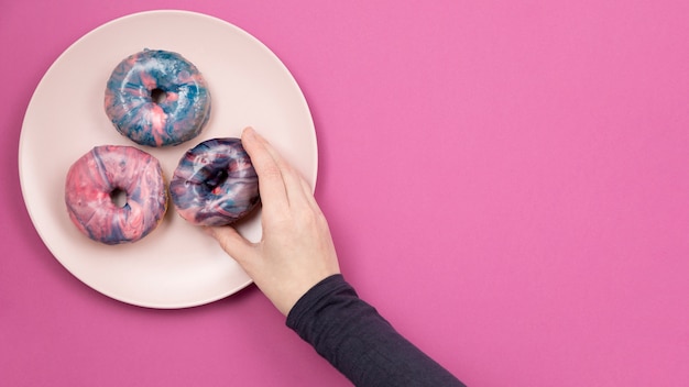 Free photo hand holding donut flat lay