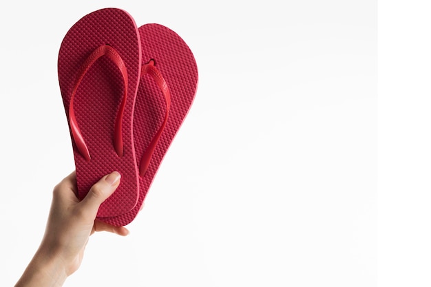 Hand holding flip-flops with copy space