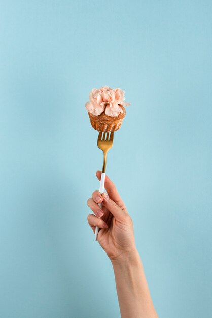 Hand holding fork with cupcake