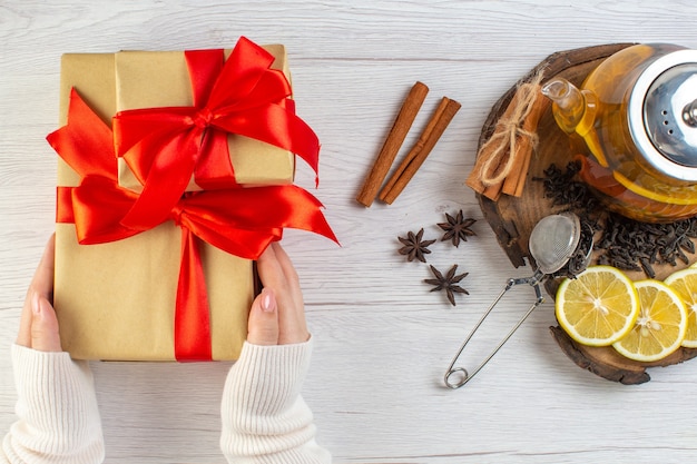 Hand holding gift with red ribbon black tea with lemon