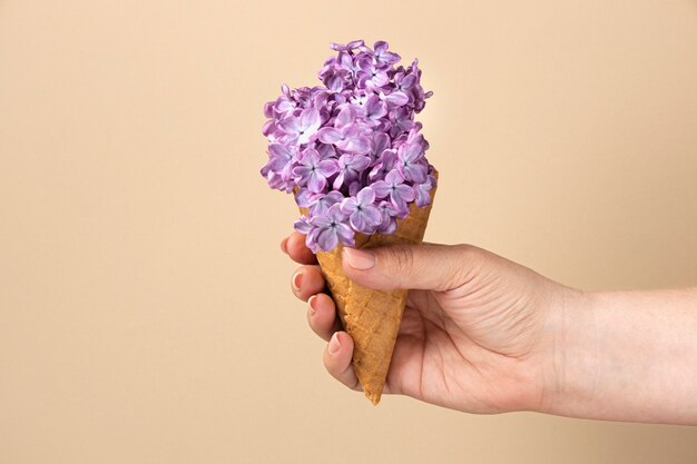 Hand holding ice cream cone with flowers