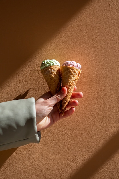 Free photo hand holding ice cream cones outside