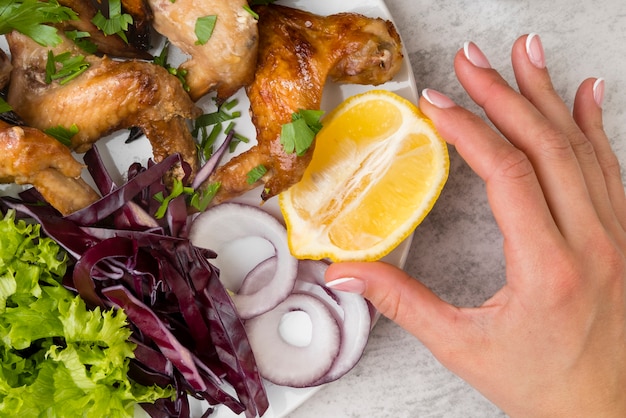 Free Photo hand holding a lemon close to chicken wings