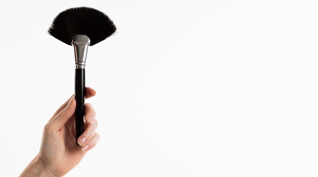 Hand holding make-up brush with copy space