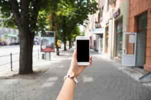 Free photo hand holding mobile with blank screen at street