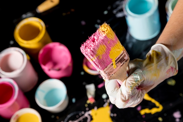 Hand holding paint brush with colored paint