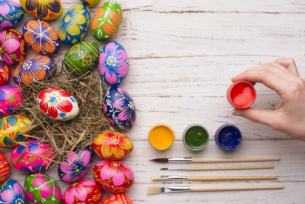 Hand holding a paint jar next to easter eggs