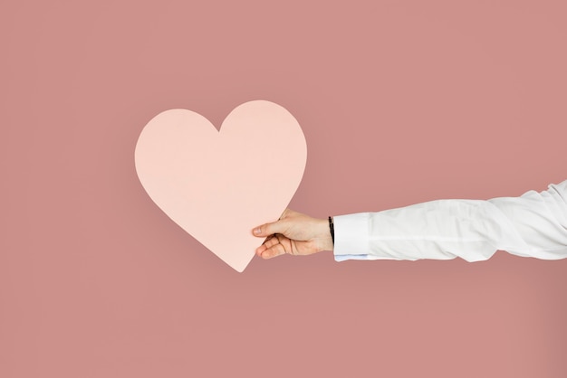 Free photo hand holding a pink heart cutout, healthy heart or love concept