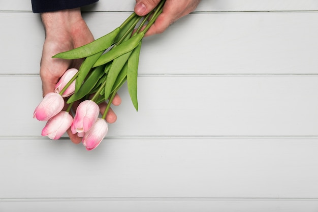 Free photo hand holding pink tulips bouquet