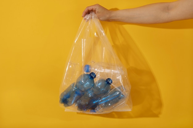 Free photo hand holding plastic bag with bottles