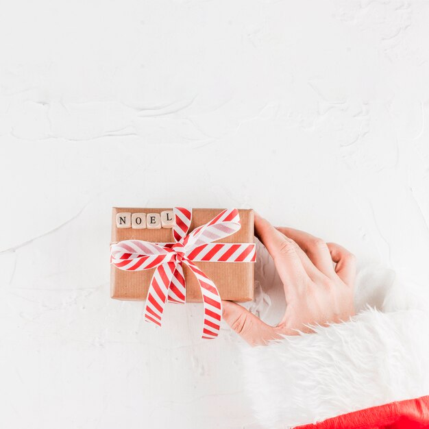 Hand holding present box with noel inscription