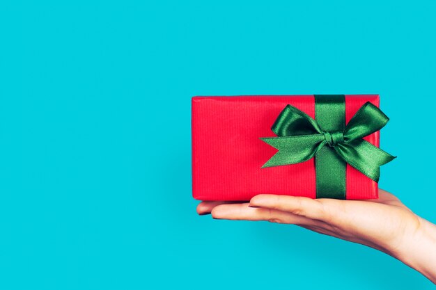 Hand holding a red gift with green bow