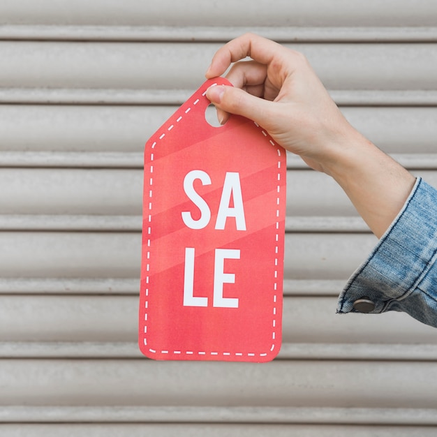 Free photo hand holding sale sign near profiled sheeting wall