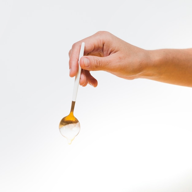 Hand holding spoon with falling cream