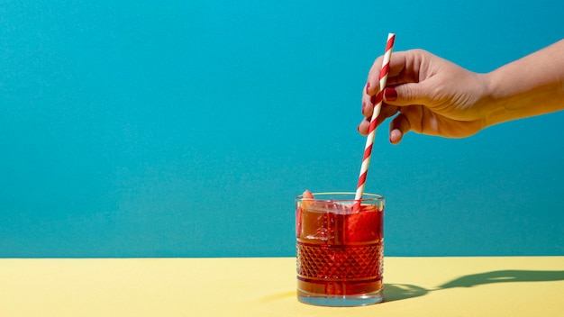 Free photo hand holding straw with sangria drink