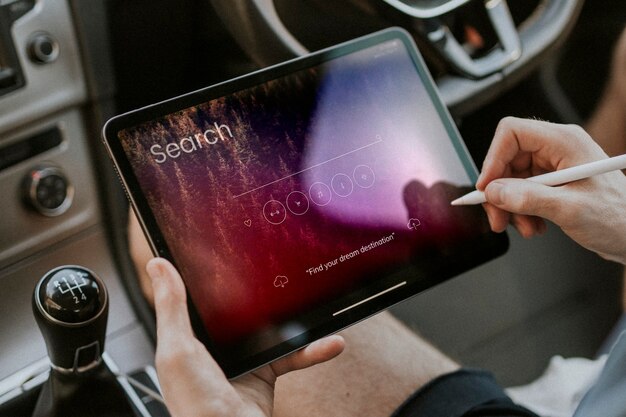 Hand holding stylus pen searching on a tablet in a car