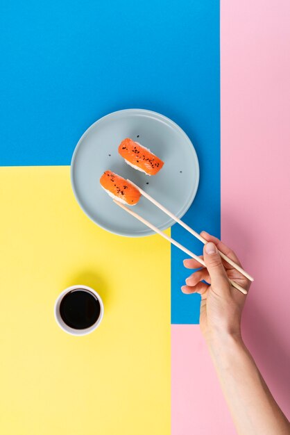 Hand holding sushi with chopsticks close up