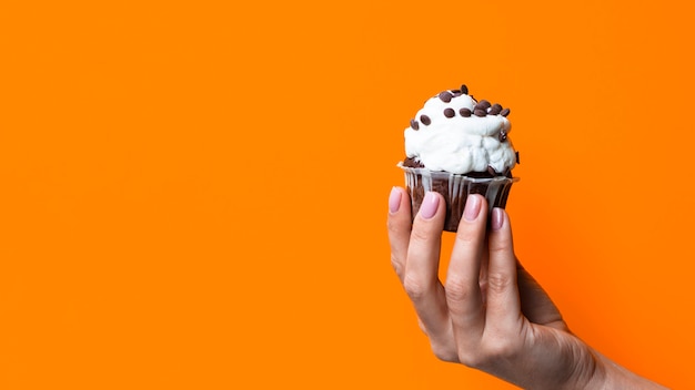 Free photo hand holding tasty muffin with copy space