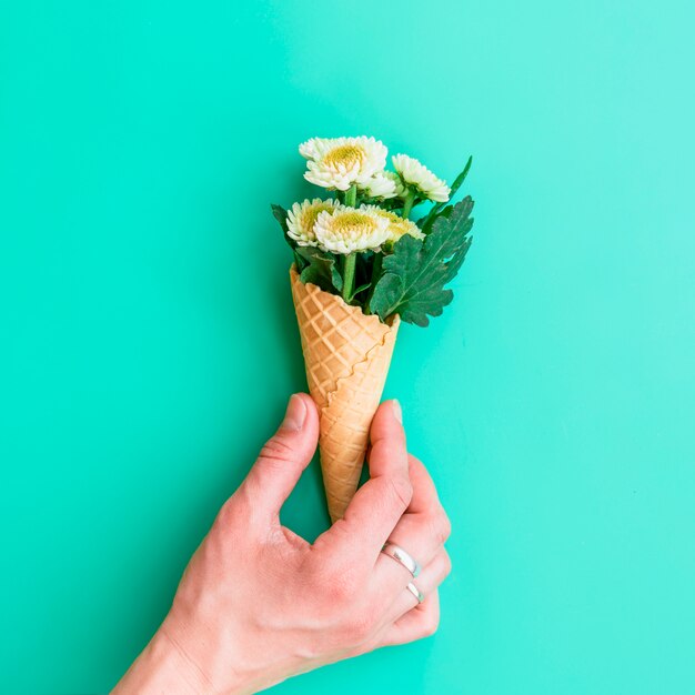 Hand holding waffle cone with white flowers