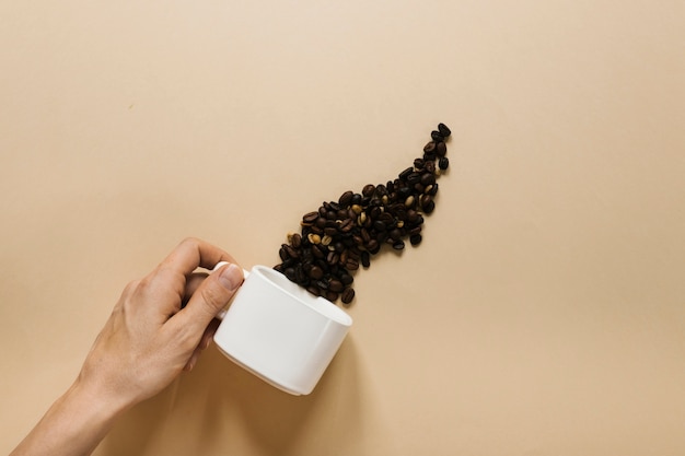 Free Photo hand holding white cup with coffee beans