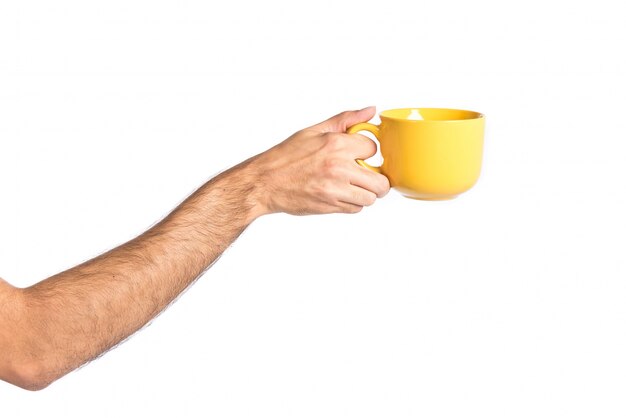 hand holding a yellow coffee cup over white