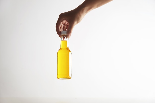 Hand holds closed rustic glass bottle with tasty cold drink inside