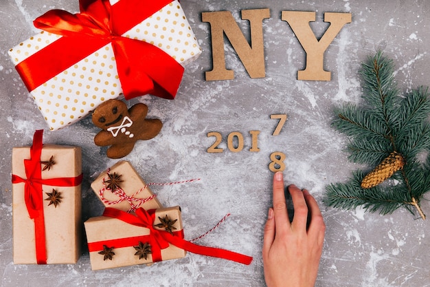 Free Photo hand makes number 2017 to 2018 on grey floor covered with christmas present boxes