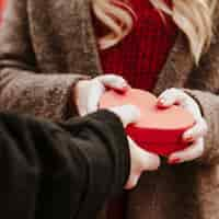 Free photo hand of man giving heart box present to woman