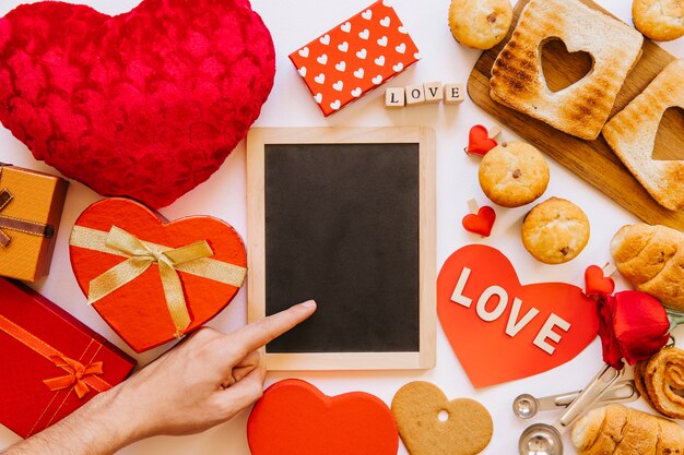 Hand near blackboard amidst pastry and gifts