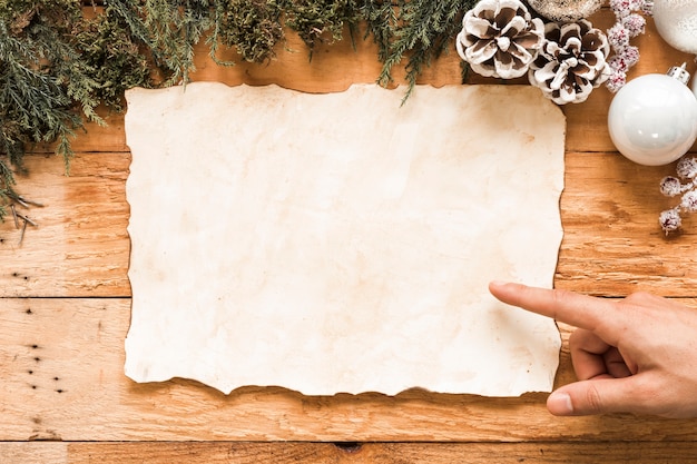 Hand near paper between Christmas decorations 