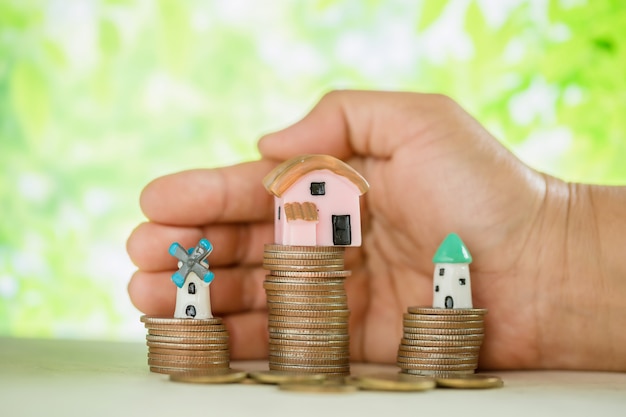 Free Photo hand pampered coins and small house model