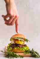 Free photo hand pointing to a delicious hamburger