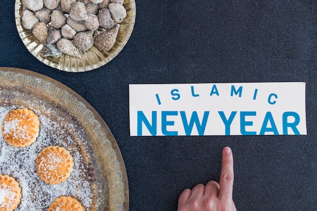 Free Photo hand pointing at islamic new year at desserts 