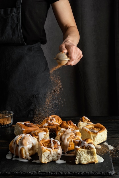 Hand pouring cinnamon on dessert close up