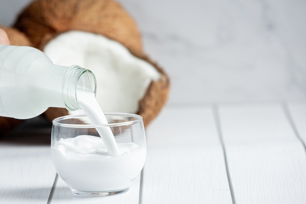 Free Photo hand pouring coconut milk from bottle to glass