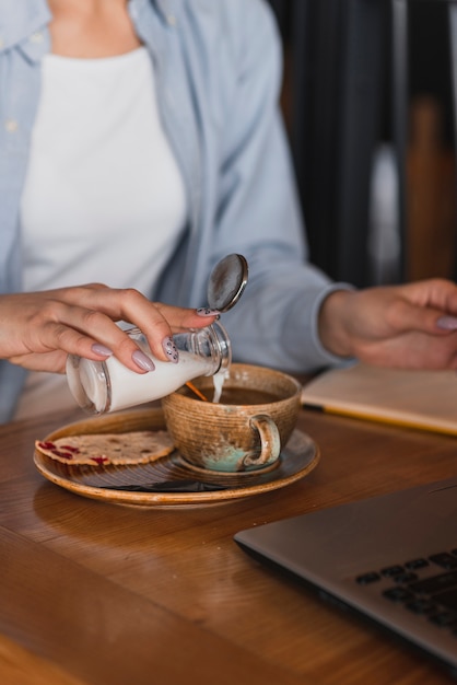 Free Photo hand pouring milk in a cup of coffee