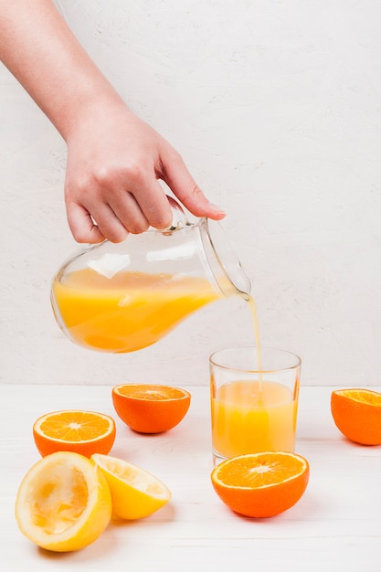 Free photo hand pouring orange juice in glass