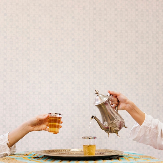 Hand pouring tea into glass