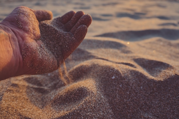 Free photo hand pours out sand.