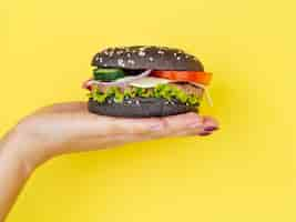 Free photo hand presenting perfect cheeseburger