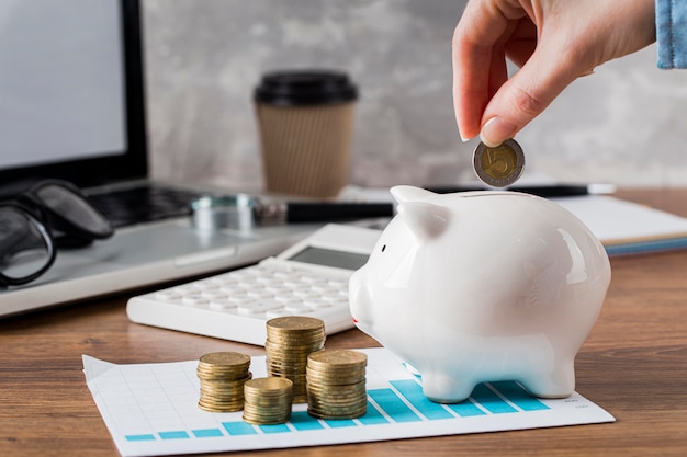 Hand putting coin in piggy bank and growth chart