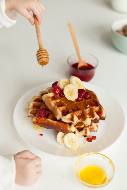 Free Photo hand putting honey on waffle