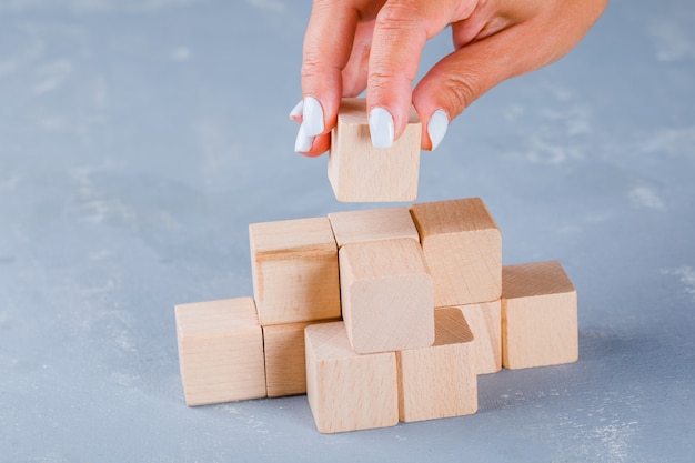 Hand putting and stacking wooden cubes