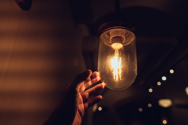 Hand reaching for a vintage light bulb.