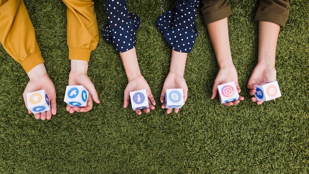 Free Photo hand's holding social media app icons blocks on green grass