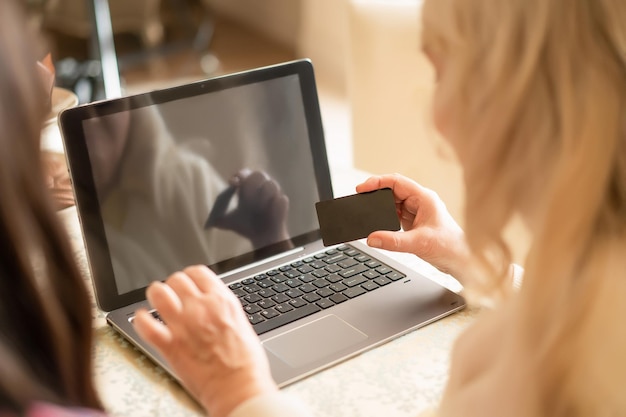 Free Photo hand of senior lady holding a banking card and entering the pin code for checking finance